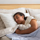 Woman sleeping peacefully in bed demonstrating the impact of bedroom lighting on sleep and mood.
