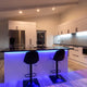Modern kitchen lighting fixtures illuminate a stylish kitchen with sleek cabinetry and a blue-lit island.