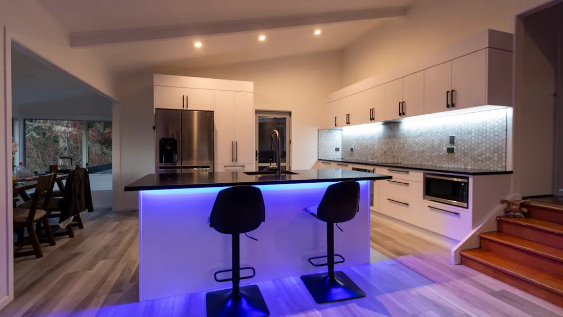 Modern kitchen lighting fixtures illuminate a stylish kitchen with sleek cabinetry and a blue-lit island.