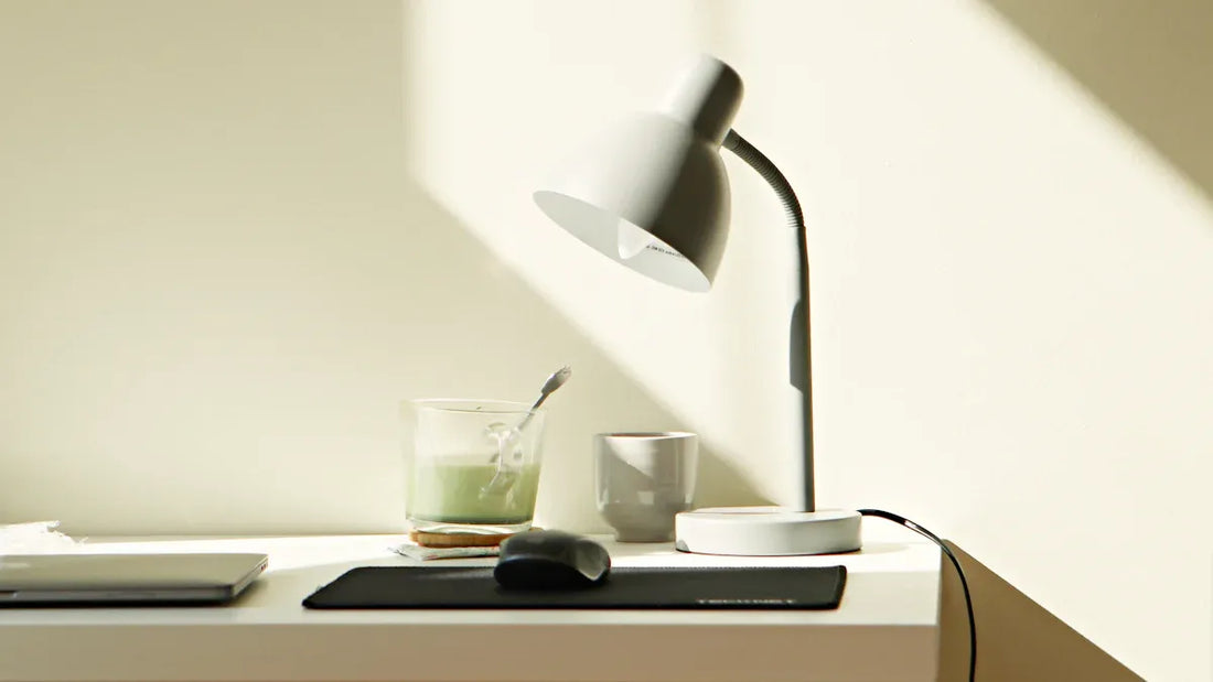 A modern workspace featuring an energy-efficient LED lamp, a laptop, and a refreshing drink on a desk.
