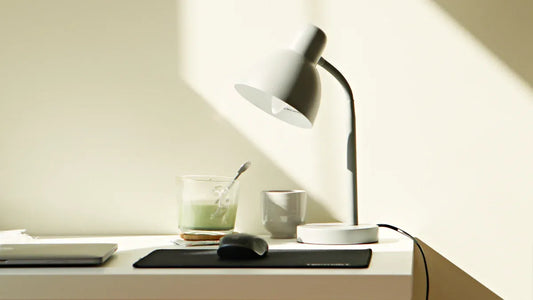 A modern workspace featuring an energy-efficient LED lamp, a laptop, and a refreshing drink on a desk.