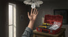 Person reaching for a light bulb while holding tools, illustrating light troubleshooting steps.